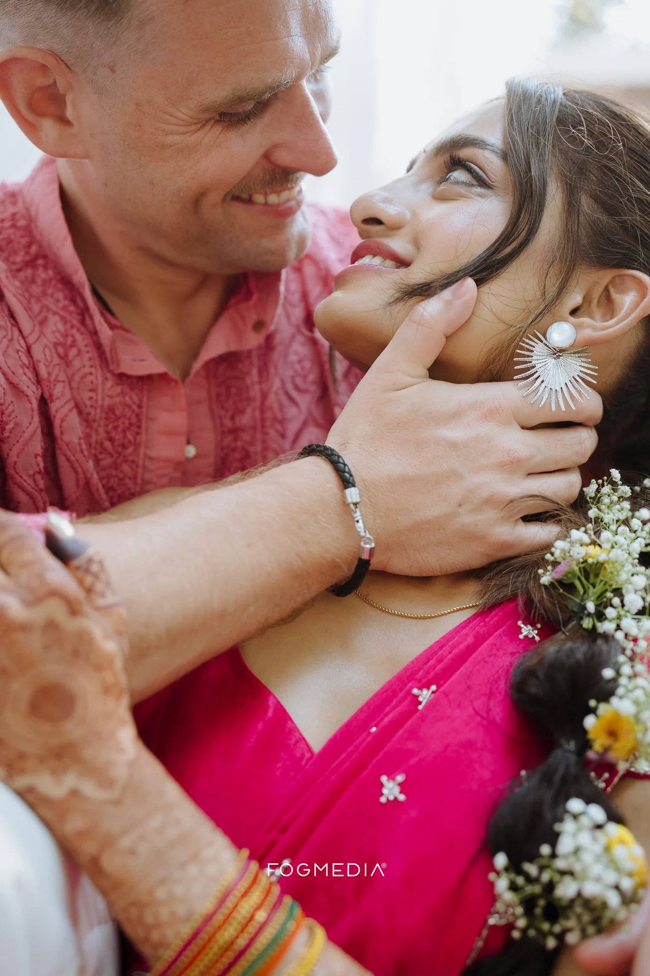 David with his hand at Salonee's jaw, both in pink, on the morning of their haldi at Prainha