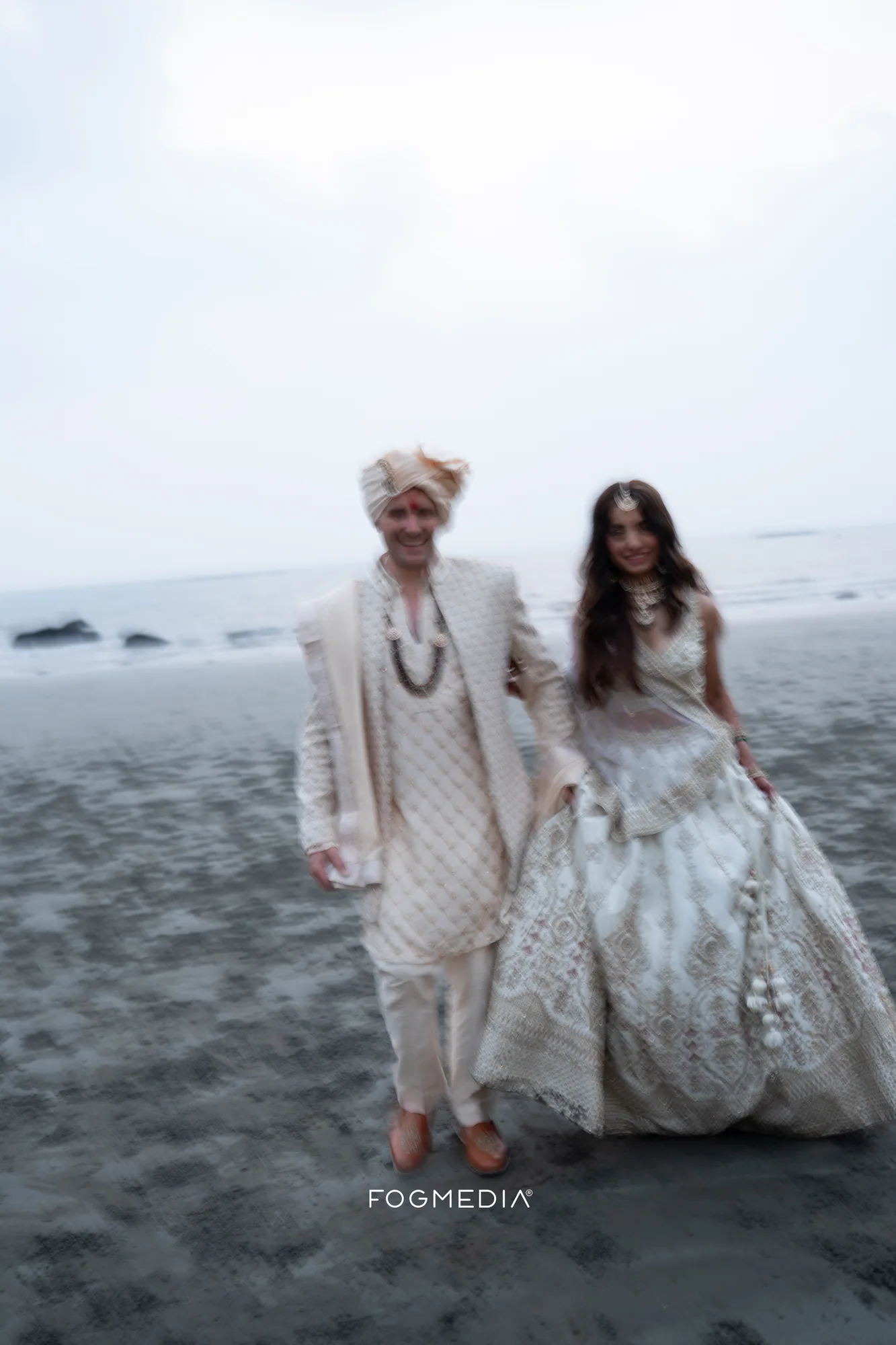 Salonee and David walking across the wet sand at Prainha beach, Dona Paula, after their wedding ceremony