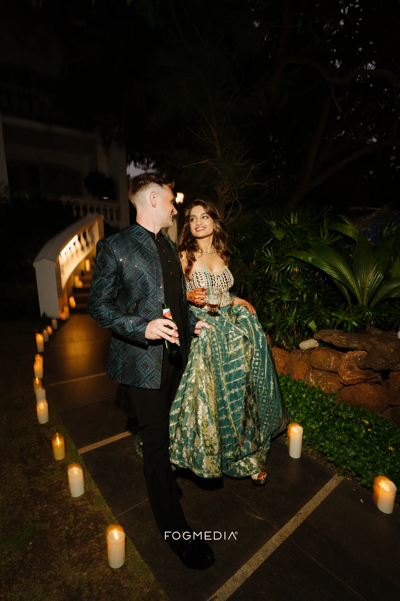 Salonee and David walking a candlelit path at Prainha Resort late in the Sangeet night