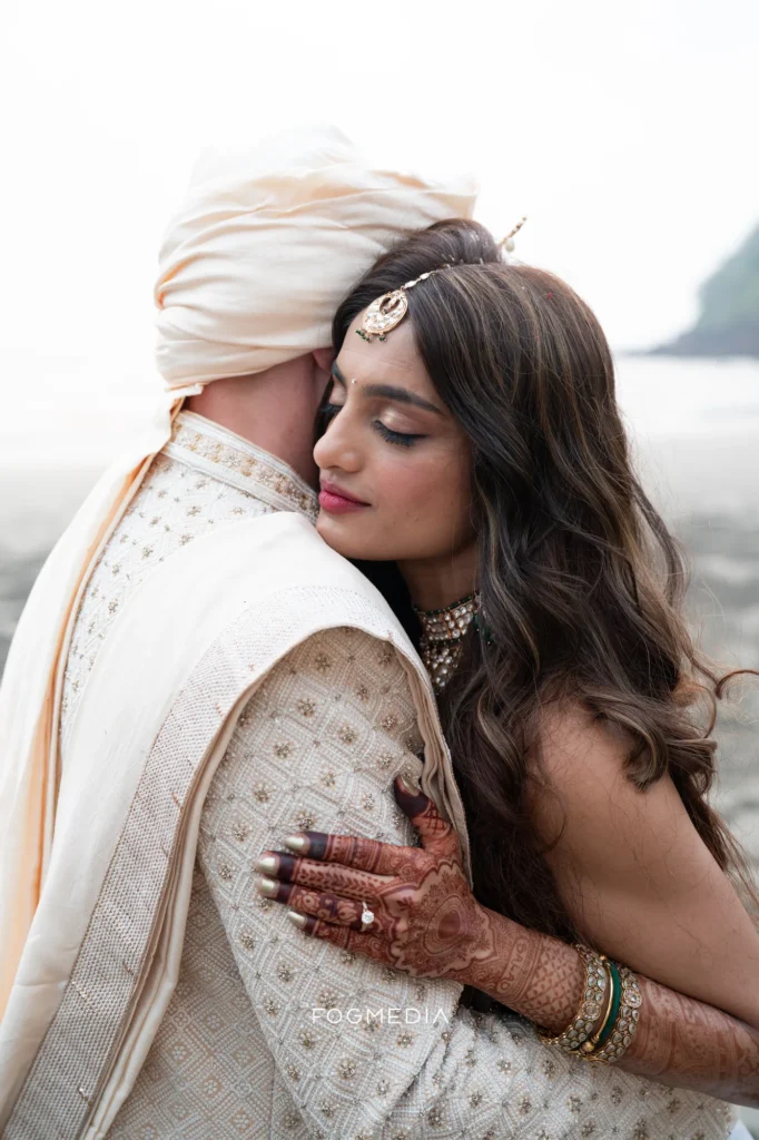 Salonee with her eyes closed against David's shoulder on the beach at Dona Paula