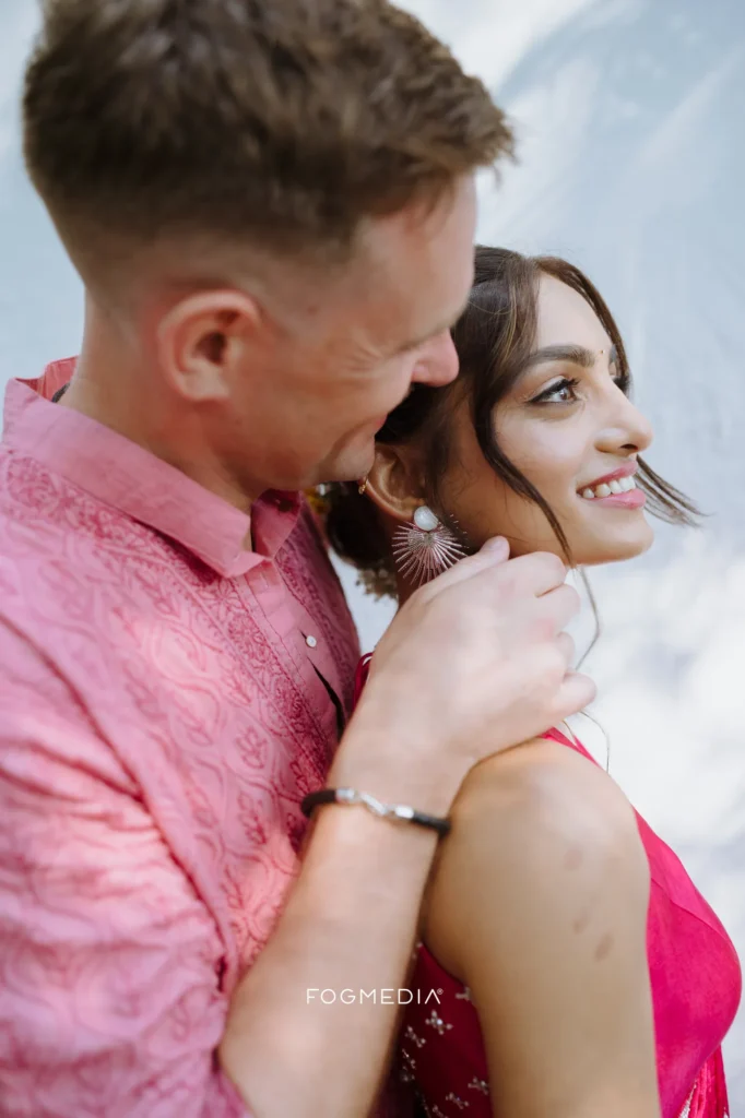 Salonee and David in pink against a white wall on their haldi morning at Prainha Resort